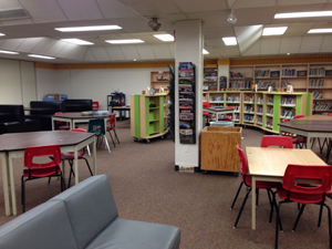 picture of a learning commons in halton with computers, tables and bookselves